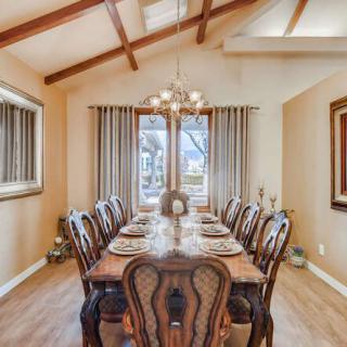 An elegantly decorated dining room with a wooden table and chairs, illuminated by a chandelier.