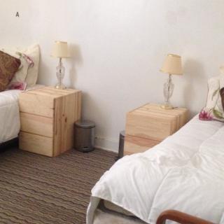 A minimalist bedroom featuring twin beds with wooden nightstands and lamps.