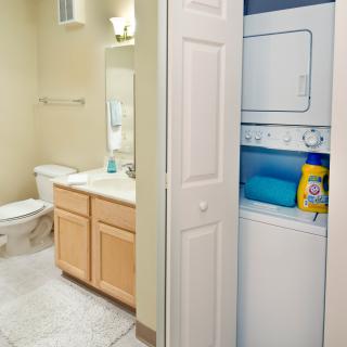 A compact bathroom with an adjacent laundry area featuring a stackable washer and dryer.