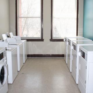 A clean and organized laundry room with multiple washing machines and dryers.