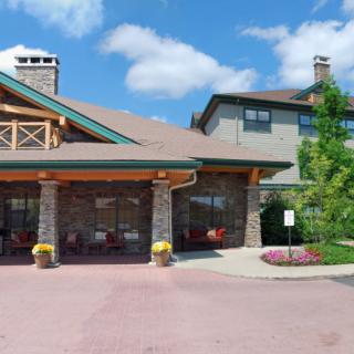 A hotel's main entrance with stone and wood architecture, featuring landscaping and patio seating.