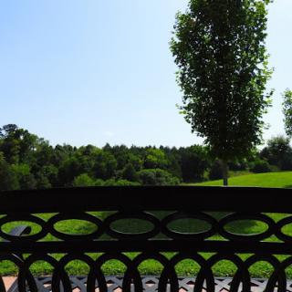 A peaceful view from a bench overlooking lush greenery and a clear blue sky.