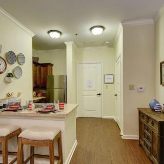 A cozy kitchen and dining area featuring bar stools, decorative plates on the wall, and warm wood flooring.