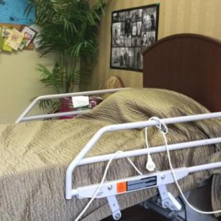 A hospital bed with a blanket in a room equipped with medical equipment and decorations.