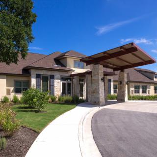 A modern residential house with a landscaped front yard and circular driveway.
