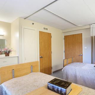 A cozy dormitory room featuring two beds, a mirror, and wooden doors.