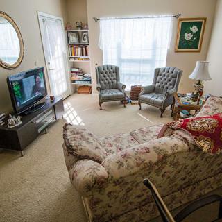 A cozy living room with a floral couch, two patterned chairs, and a television.