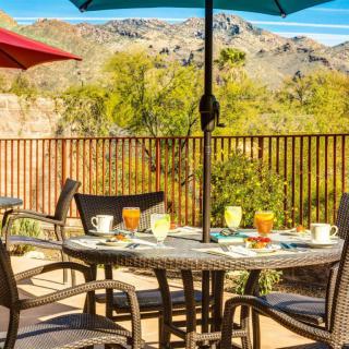 A patio table set for outdoor dining with a desert mountain view.