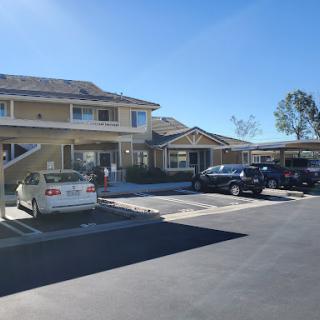 A sunny day at a residential building with parked cars and a well-maintained exterior.