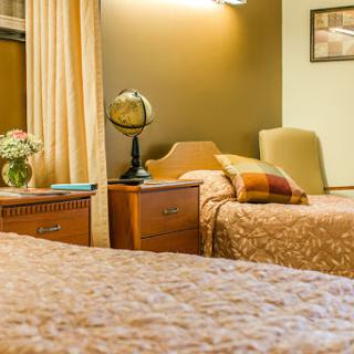A cozy bedroom featuring twin beds, a nightstand with a lamp, and decorative elements.
