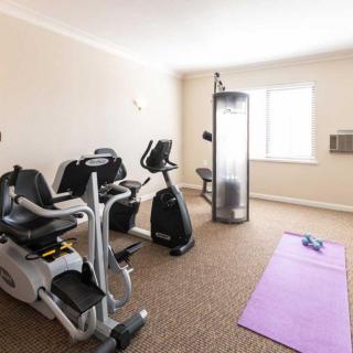 A well-lit home gym with exercise bikes, a purple yoga mat, and dumbbells.