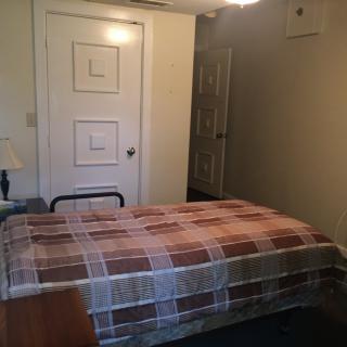 A simple bedroom with a single bed and patterned blanket.