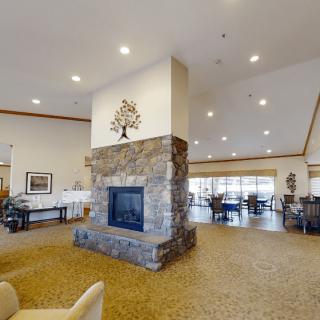 A spacious and modern lobby featuring a central stone fireplace with surrounding seating.