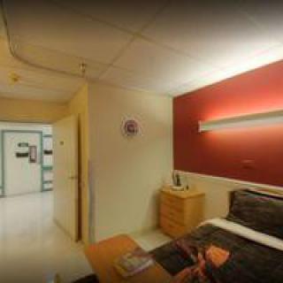 A well-lit hospital room with a comfortable bed and modern furnishings.