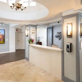 A modern reception area featuring a sleek desk, chandelier, and stylish decor.
