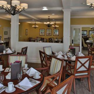 An elegant dining room with neatly arranged tables and chairs, featuring chandeliers and tasteful interior decor.