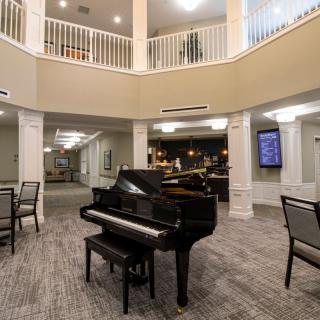 A grand piano in a spacious lobby area with seating and elegant architecture.