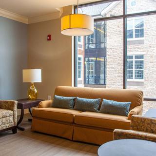 A cozy living room with a sofa, chairs, and large window.