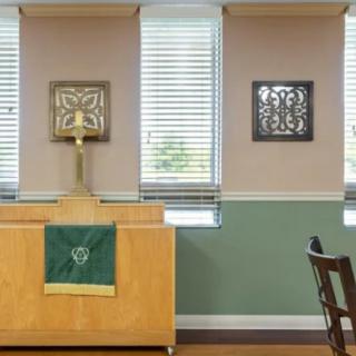 A simple chapel interior featuring an altar with a cross and religious decor on the walls.
