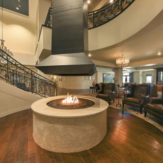 A luxurious living room featuring a modern fireplace, spiral staircase, and elegant seating.
