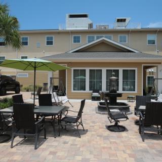 A sunny patio area with outdoor furniture and umbrellas in front of a residential building.