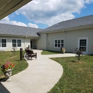 A serene courtyard featuring a paved pathway and lush green surroundings under a partly cloudy sky.