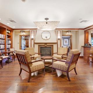 A cozy living room with a fireplace and comfortable seating, surrounded by bookshelves.