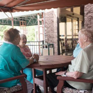 A group of seniors sitting together and socializing on a patio.