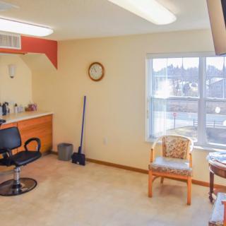 A tidy hair salon setup featuring a styling chair, mirror, and large window.