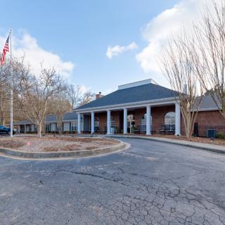 A building entrance with columns and an American flag in the parking lot.