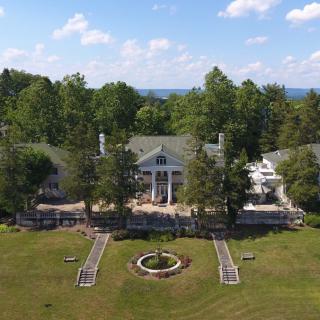 Aerial view of a grand mansion surrounded by trees and landscaped gardens.