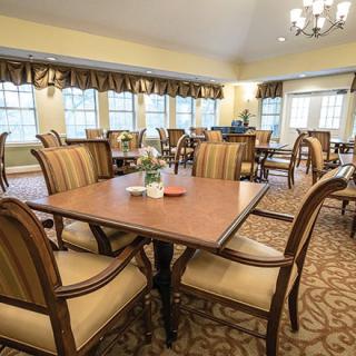 A well-furnished dining area with elegant tables and chairs, featuring large windows and soft lighting.