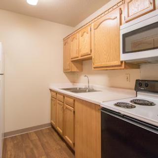 A cozy kitchen featuring wooden cabinets, modern appliances, and a warm atmosphere.