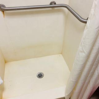 A view of a shower space showing signs of wear and staining.