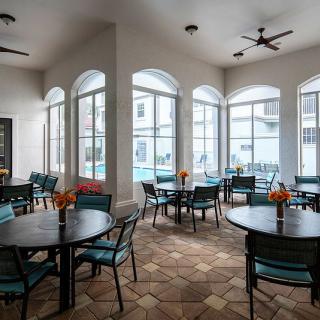 A bright dining area with tables and chairs, featuring large windows and stylish decor.