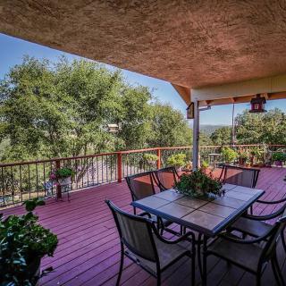A spacious wooden patio deck with outdoor furniture and a scenic view of trees.