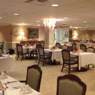 An elegant dining room with neatly arranged tables and chairs, featuring a chandelier.