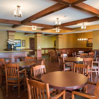 A cozy dining area featuring wooden tables and chairs, with warm lighting and a welcoming ambiance.