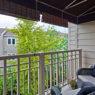 A cozy balcony with outdoor seating and a view of lush greenery.