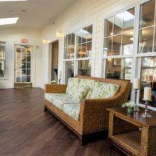 A cozy living room with a wooden sofa, side table, and large windows letting in ample light.