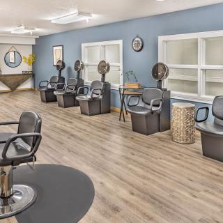 A modern hair salon interior featuring styling stations and hair dryers.
