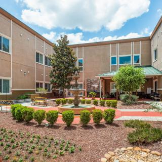 A view of a landscaped courtyard with a brick building in the background.