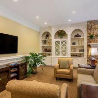 A cozy living room with comfortable seating, built-in shelves, and a large television.