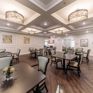 A well-decorated dining room with neatly arranged tables and chairs, elegant lighting, and tasteful artwork on the walls.