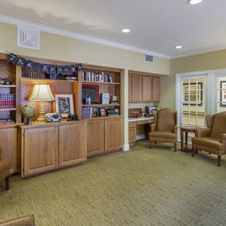 A cozy room with wooden bookshelves, comfortable chairs, and decorative items.