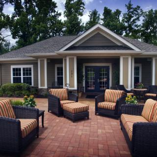 A cozy outdoor patio with wicker furniture arranged in front of a charming house.