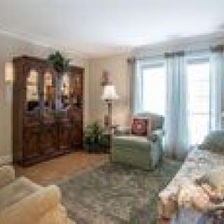 A cozy living room with a sofa, armchair, and a wooden cabinet.