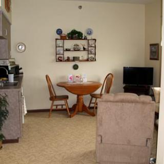 A cozy living space featuring a dining table with chairs, a TV, and decorative shelving.