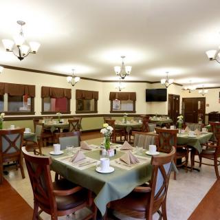 A cozy dining area with neatly arranged tables and chairs, featuring elegant table settings.