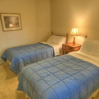 A cozy bedroom with twin beds and a warm lamp illuminating the nightstand.